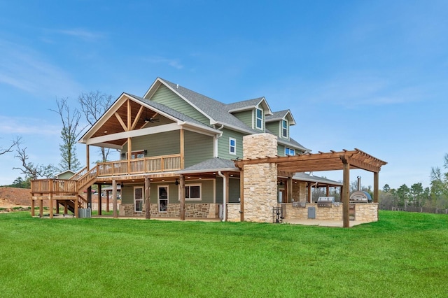 rear view of property featuring a yard, a patio, an outdoor kitchen, a pergola, and a wooden deck