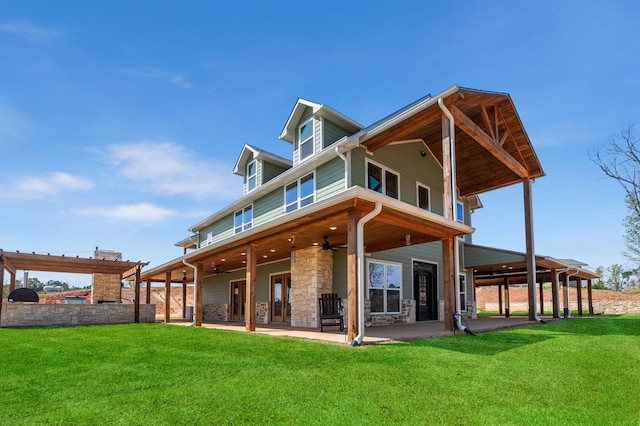 rear view of property featuring a yard, stone siding, a patio area, and a ceiling fan