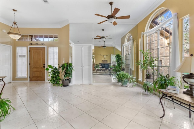 entrance foyer with crown molding, light tile patterned floors, visible vents, ceiling fan, and baseboards