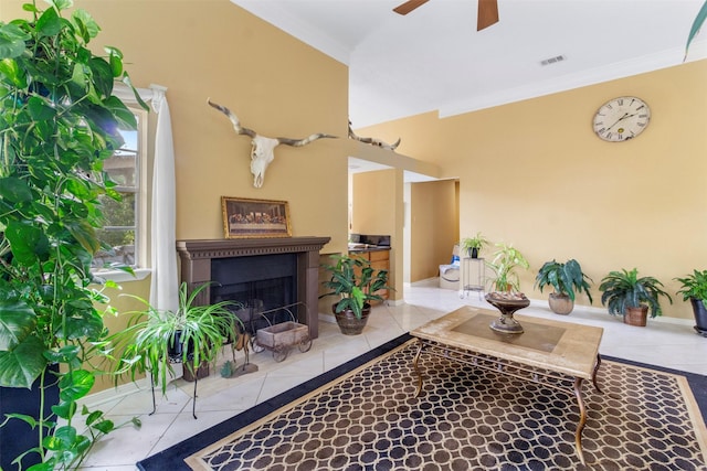 living room with visible vents, ceiling fan, tile patterned flooring, crown molding, and a fireplace