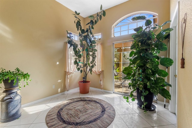 foyer entrance with a high ceiling, baseboards, and light tile patterned flooring