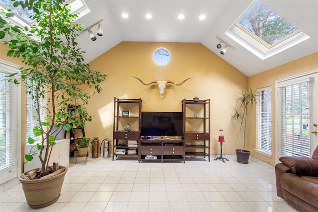 living room with vaulted ceiling with skylight, track lighting, and tile patterned floors