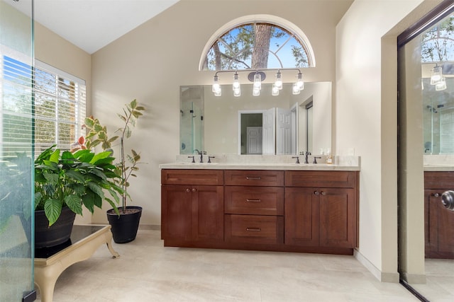 bathroom featuring double vanity, vaulted ceiling, a sink, and tile patterned floors