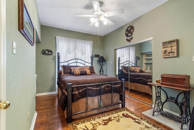 bedroom featuring a ceiling fan, vaulted ceiling, a textured ceiling, baseboards, and hardwood / wood-style flooring