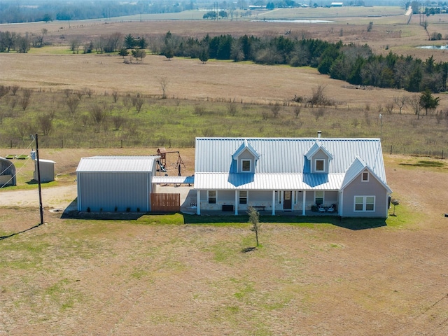 view of front of house with a front yard, metal roof, an outbuilding, and a rural view