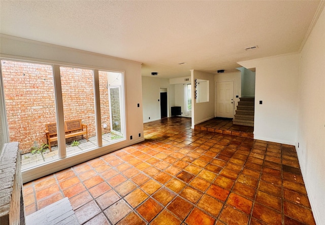 tiled spare room featuring baseboards, stairs, visible vents, and a textured ceiling