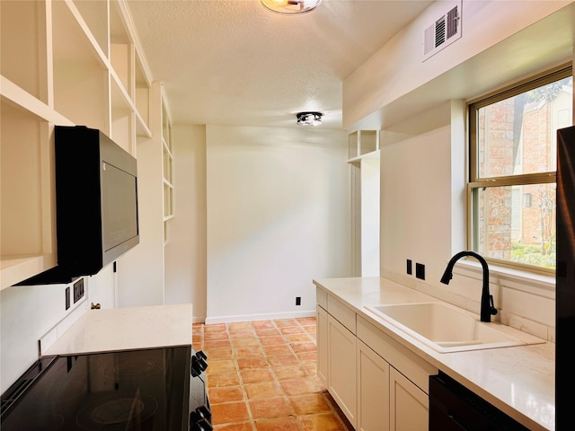 kitchen with black appliances, light countertops, a sink, and visible vents