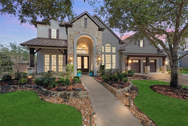 view of front of property featuring french doors, concrete driveway, a lawn, a standing seam roof, and metal roof