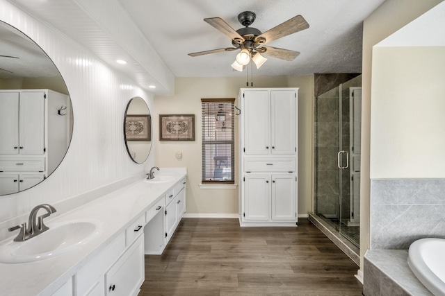 full bath with a stall shower, ceiling fan, a sink, and wood finished floors