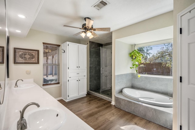 bathroom with a stall shower, visible vents, a sink, and wood finished floors