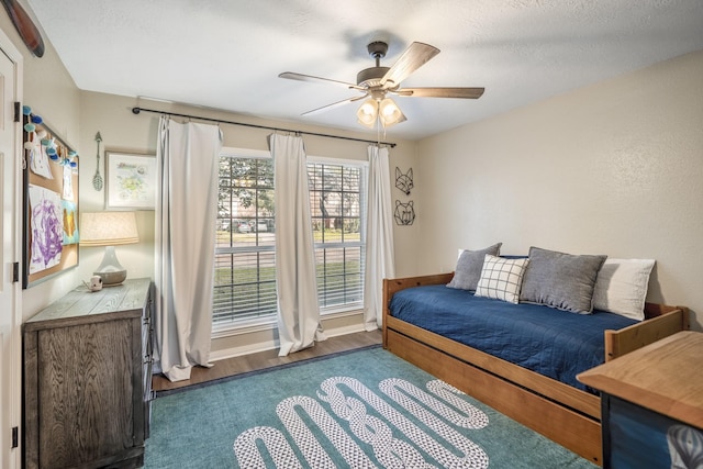 interior space with ceiling fan, a textured ceiling, and wood finished floors