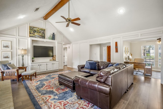 living room with ceiling fan, a decorative wall, wood finished floors, visible vents, and beamed ceiling