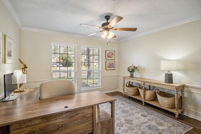 home office with ceiling fan, ornamental molding, dark wood-style flooring, and a wainscoted wall