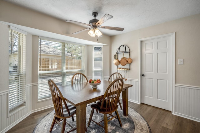 dining area with a wainscoted wall, a textured ceiling, and wood finished floors