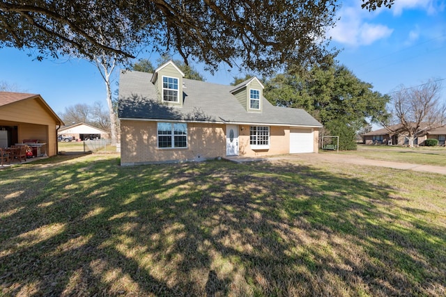 cape cod house with an attached garage, dirt driveway, a front yard, and brick siding