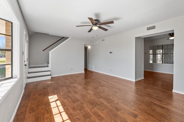 unfurnished living room with visible vents, baseboards, ceiling fan, stairway, and wood finished floors