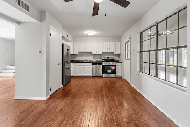 kitchen featuring visible vents, white cabinets, dark countertops, dark wood-style floors, and appliances with stainless steel finishes