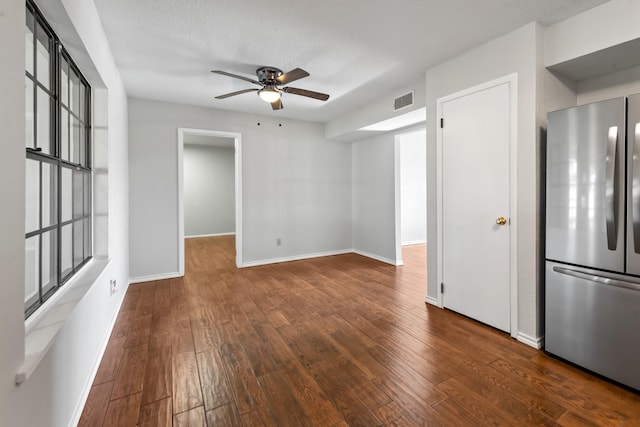 unfurnished room with visible vents, baseboards, a ceiling fan, wood-type flooring, and a textured ceiling