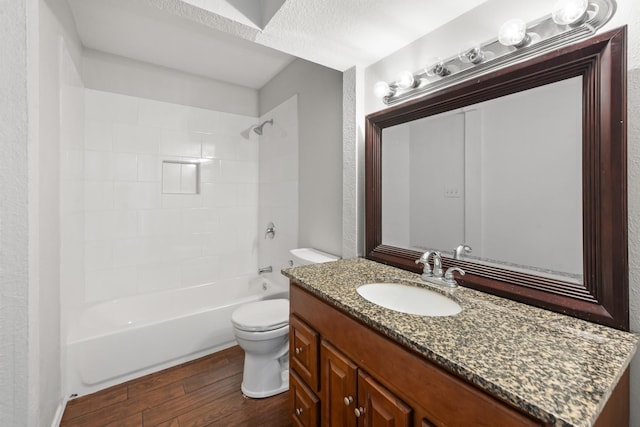 bathroom featuring toilet, tub / shower combination, wood finished floors, and vanity