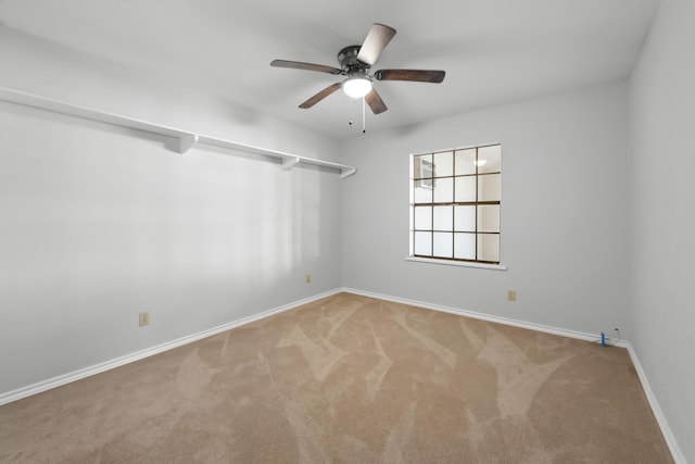 carpeted spare room featuring ceiling fan and baseboards