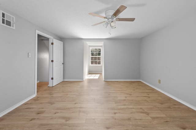 unfurnished room with light wood-style floors, baseboards, visible vents, and a ceiling fan