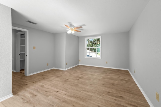 empty room with light wood finished floors, ceiling fan, visible vents, and baseboards