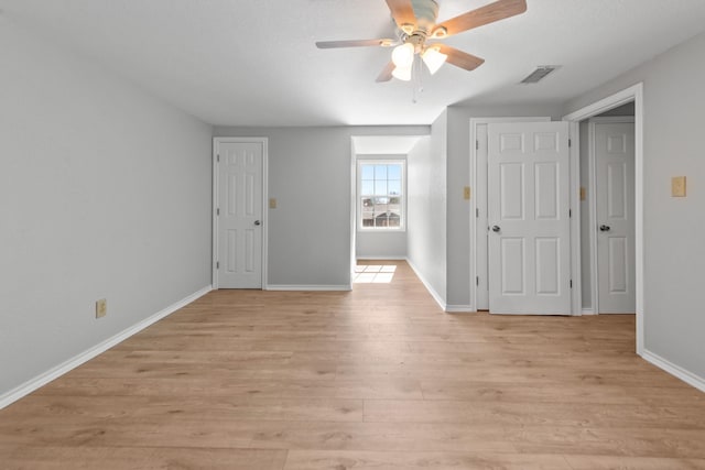 empty room with ceiling fan, light wood-type flooring, visible vents, and baseboards