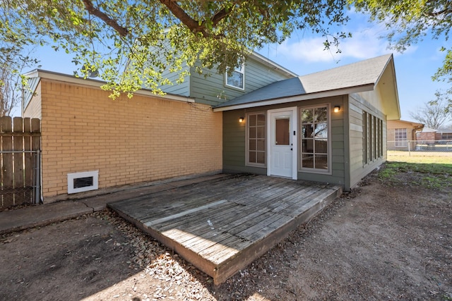 back of property with a wooden deck, fence, and brick siding