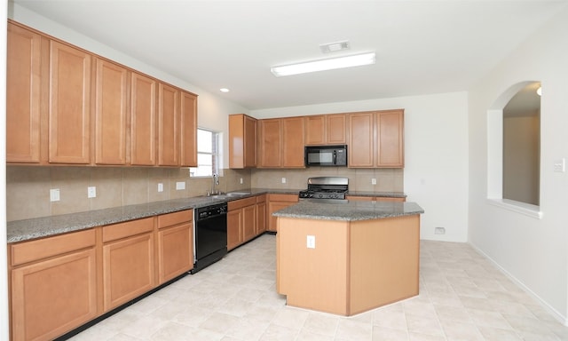 kitchen with visible vents, decorative backsplash, a center island, black appliances, and a sink