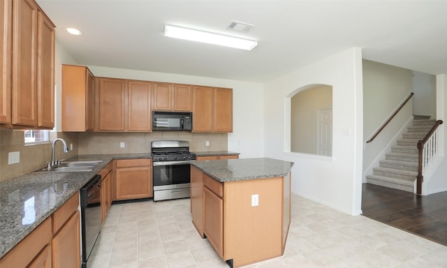 kitchen with a kitchen island, visible vents, backsplash, black appliances, and dark stone countertops