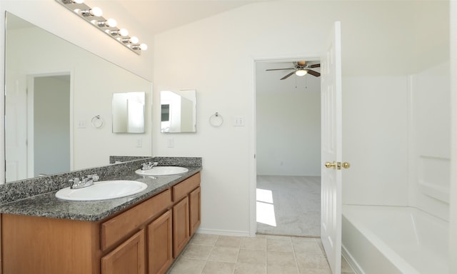 bathroom featuring ceiling fan, double vanity, a tub to relax in, and a sink