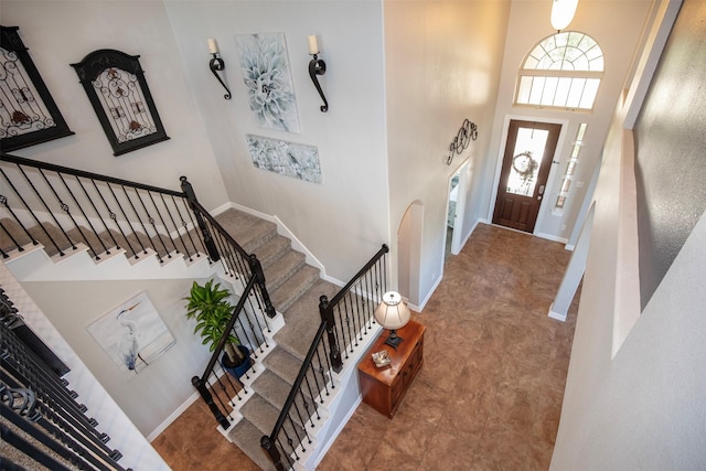 entrance foyer with a towering ceiling, stairs, and baseboards