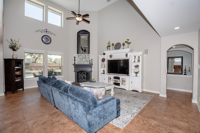 living area with a towering ceiling, baseboards, and a fireplace with raised hearth