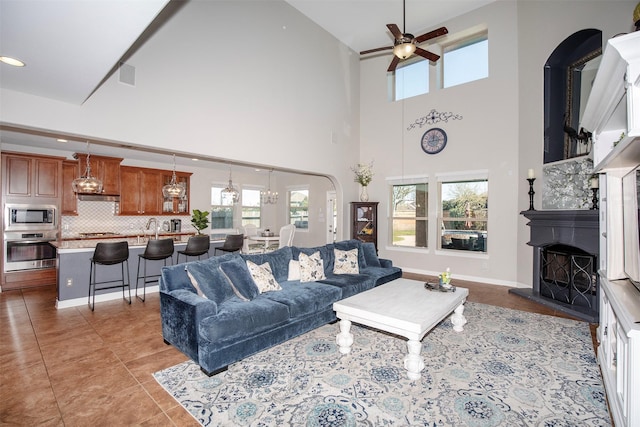 living room featuring light tile patterned floors, recessed lighting, a fireplace with raised hearth, ceiling fan, and baseboards