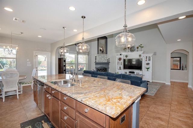 kitchen with arched walkways, brown cabinets, a fireplace, a sink, and recessed lighting