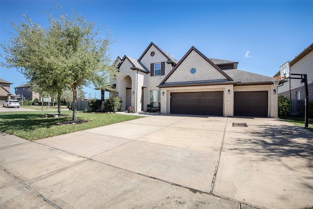 french provincial home with an attached garage, brick siding, driveway, and a front yard