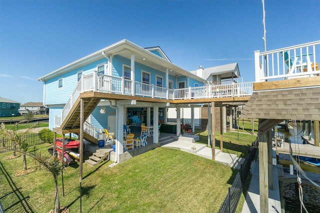 rear view of house featuring a patio, boat lift, fence, stairs, and a yard