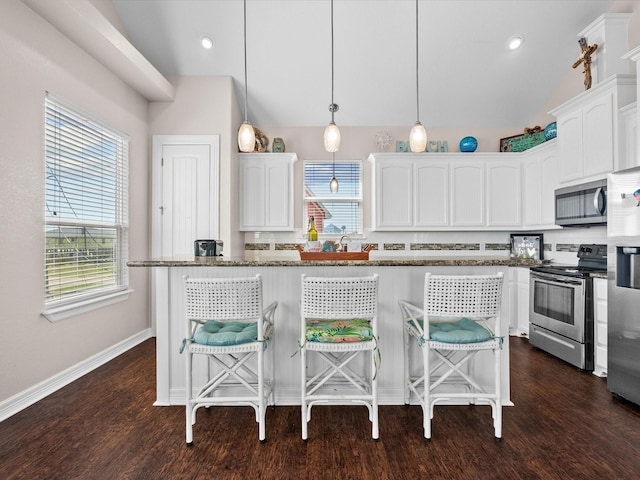 1922 Blue Water Hwy, Surfside Beach, TX 77541 - kitchen featuring appliances with stainless steel finishes, lofted ceiling, white cabinetry, a breakfast bar, and dark stone counters