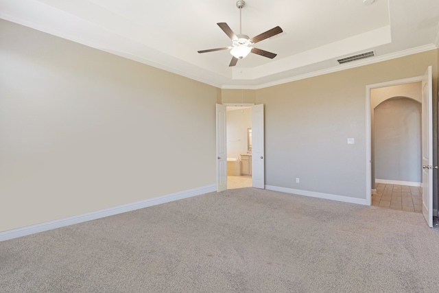 empty room featuring a raised ceiling, visible vents, light carpet, and baseboards