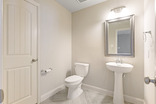 bathroom with toilet, visible vents, and baseboards