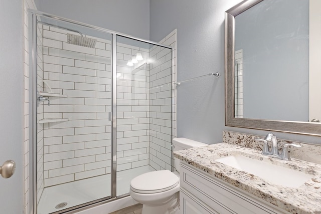 bathroom with toilet, a shower stall, and vanity