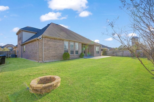 back of property featuring an outdoor fire pit, brick siding, a lawn, and a fenced backyard