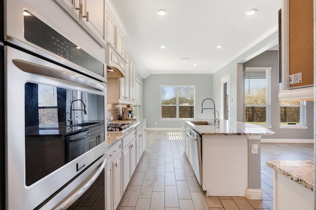 kitchen with light stone countertops, tasteful backsplash, stainless steel appliances, and a sink