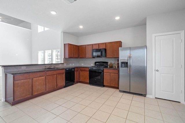 kitchen with backsplash, brown cabinetry, a sink, a peninsula, and black appliances