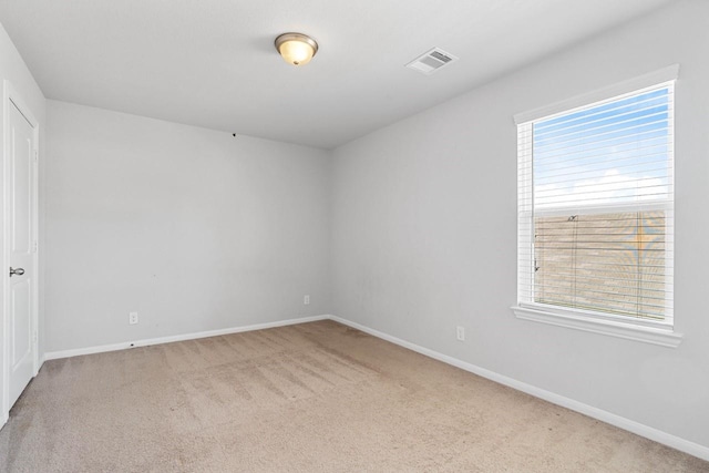 spare room featuring carpet floors, visible vents, and baseboards