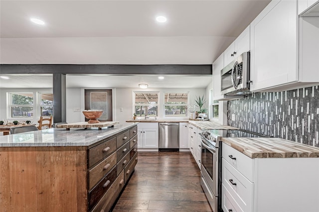 kitchen with tasteful backsplash, white cabinets, dark wood-type flooring, light stone countertops, and stainless steel appliances