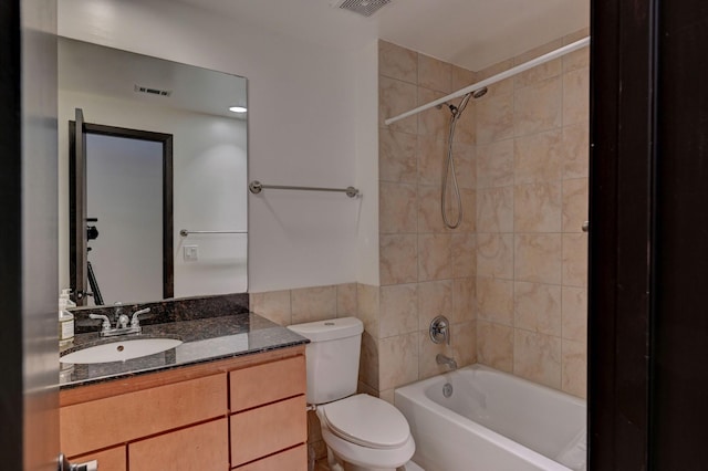 full bath featuring tile walls, visible vents, toilet, vanity, and  shower combination