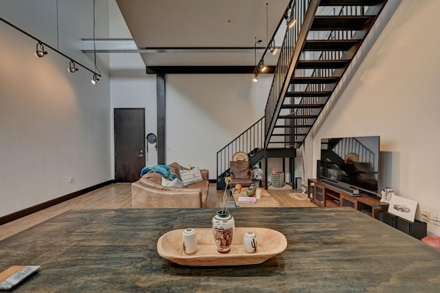 living area featuring a high ceiling, stairway, wood finished floors, and baseboards