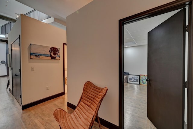 corridor featuring a drop ceiling, wood finished floors, and baseboards