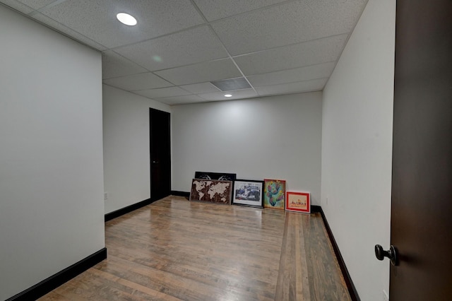 empty room with a paneled ceiling, baseboards, wood finished floors, and recessed lighting